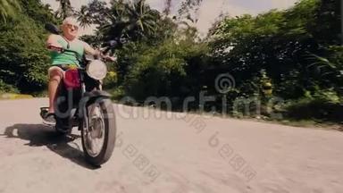 骑摩托车在热带森林景观道路上的老人。 一个骑摩托车的老人在摩托旅行