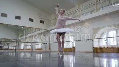 芭蕾舞演员穿着白色芭蕾舞裙在舞蹈室或健身房练习。 女人在课堂上跳古典舞。 孤独