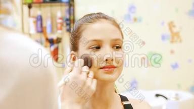 化妆师给一位年轻女士的脸上抹粉