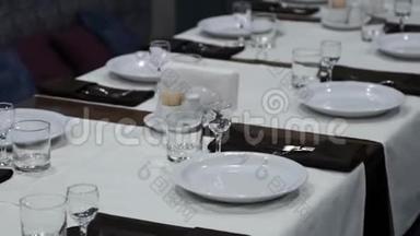 餐厅的桌子设置。 盘子、眼镜和其他厨具站在一张长桌子上。