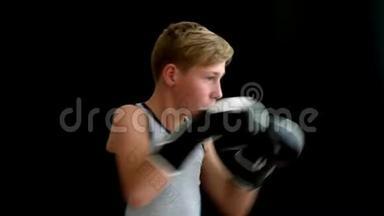 一个十几岁的运动员站在黑暗的背景上。 他的手戴着黑白手套。 男孩打了一拳，左边