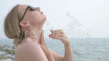 阳光明媚的夏天，一个戴太阳镜、脖子上涂防晒霜、坐在海滨的迷人少女