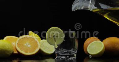 将果汁从水罐中倒入杯中，背景上倒入橘子和柠檬片