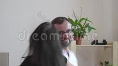 一个戴眼镜和一件白色t恤的男人和他的妻子跳舞。 一男一女在房间里<strong>走动</strong>，手牵手.. 关于