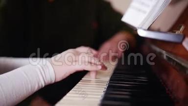 音乐课。 女孩弹钢琴，年长的老师坐在附近，帮助演奏。 右侧视图