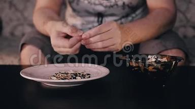 一个人吃杯中的种子，把壳扔进盘子里。 快速录像回放。