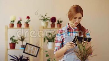 <strong>小生</strong>意。 一个穿着条纹围裙和格子衬衫的女孩，站在她的商店里，拿着一台数字平板电脑。