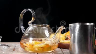蒸汽从玻璃茶壶里出来，里面有水果。 慢动作。 黑色背景。 茶道。 高清高清