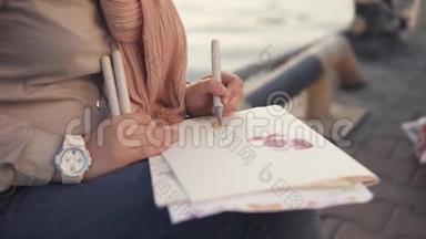 一个女人的手紧紧`，靠近大<strong>海</strong>，一个女人拿着一支笔