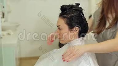 女理发师正在一家美发店里给一个年轻女孩的脖子上修领子。
