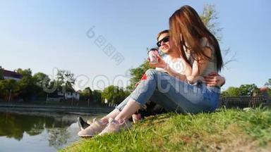 浪漫的<strong>夫妻</strong>喝咖啡，笑着坐在池塘附近的绿草上。 <strong>夫妻</strong>信任、爱情和幸福的概念