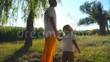 在夏天和爸爸一起穿过绿色公园的时候，小孩子抬头看着一棵高大的树。 年轻的父亲和可爱的