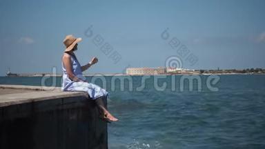 一位身穿蓝色连衣裙的年轻美女坐在湖边的一个<strong>木墩</strong>上