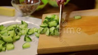 一个拿着刀的女人把切片的黄瓜放在白色的盘子里