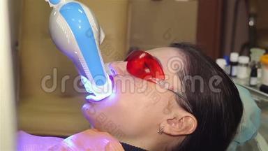 年轻女子在牙科医生办公室用紫外线`机器进行紫外线<strong>美</strong>白.
