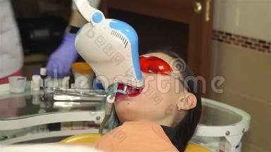 年轻女子在牙科医生办公室用紫外线`机器进行紫外线美白.