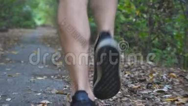 少年运动员在初秋森林中沿着小径奔跑的雄脚。 在大自然中沿着小径慢跑的运动男子的腿
