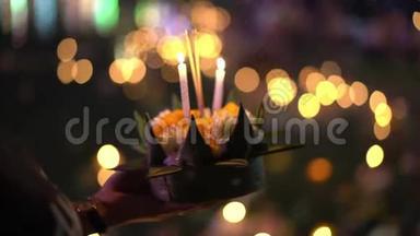 慢镜头：一个人手里拿着一支燃烧的蜡烛，手里拿着一支克拉通。 庆祝泰国传统节日