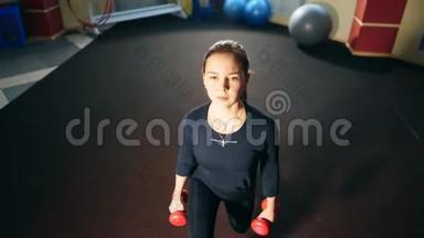 <strong>健身</strong>房里的女孩用哑铃做午<strong>餐</strong>。 锻炼大腿和臀部的肌肉。