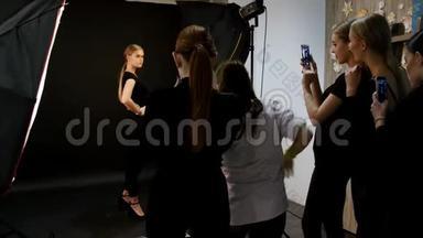 年轻女子模特在摄影棚拍照。 穿着黑色衣服射杀模特。 全高射击