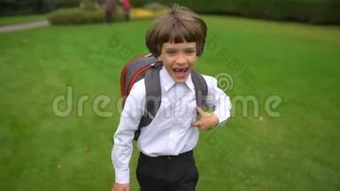 <strong>一年级</strong>学生，小学学生，带着背包在户外上学和跑步的小男孩微笑