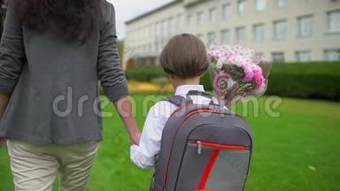 母亲牵着小儿子的手，背着背包去户外上学，<strong>一年级</strong>学生，小学，第一