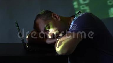 一个黑屋子里的黑客在电脑旁睡着了。使用程序代码。网络犯罪的概念。