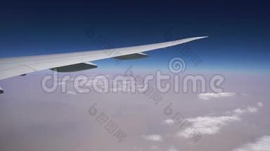 飞机在白云上方高空飞行.. 窗户里飞机的机翼。 空中飞行