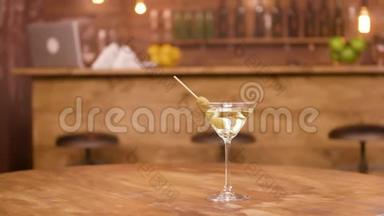 马提尼酒杯的<strong>视差</strong>镜头放在空木桌上，背景酒吧柜台