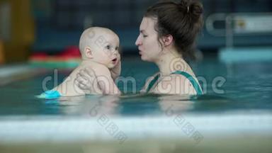 女人教他的小儿子在游泳池里潜水。 孩子有一张惊讶的脸。 加强免疫力，发展