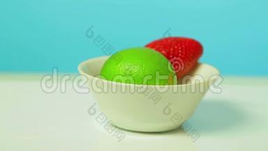 青柠色的水果和成熟的草莓浆果放在白色的盘子里旋转成一圈。