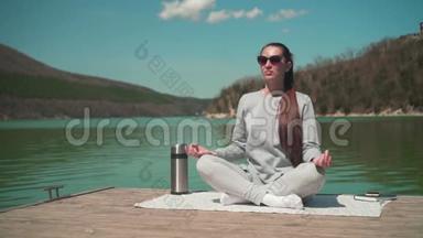 春天的一天，一位年轻女子坐在湖边的<strong>木墩</strong>上，在阳光下冥想，在大自然中放松。