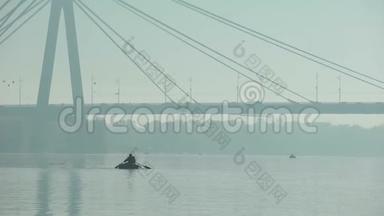 乘坐<strong>充气船</strong>在大桥下航行的渔夫，雾蒙蒙的天气，大城市