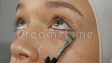 一个专业的化妆师用特殊的画笔将<strong>遮瑕</strong>膏应用于女孩模型。 高级时尚，拍摄视频