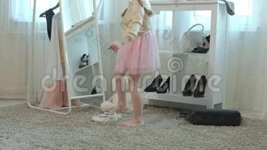 穿着粉红色裙子扎着辫子的开朗的小女孩穿着妈妈`高跟鞋，在镜子前跳舞。