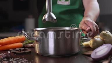 厨师用手搅拌机在金属锅中煮汤，煮健康食品，捣碎蔬菜，全高清道具