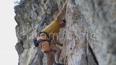 年轻的攀岩者开始在悬崖上攀岩，寻找，伸手抓住。
