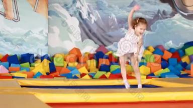 小女孩跳在蹦床上，在孩子们`操场上玩耍。 儿童游戏。