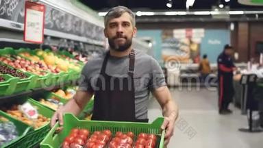 水果和蔬菜部超市里，一个年轻的推销员穿着围裙，背着一盒西红柿