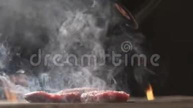 烤肉牛排。 生火做饭。 慢动作牛肉牛排特写.. 厨师用香料和胡椒洒肉。