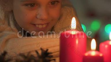 兴奋的<strong>女孩</strong>看着燃烧的蜡烛，在圣诞节<strong>许愿</strong>，特写