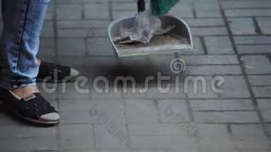 穿牛仔裤的女人正在把白色地板上的碎片扫到街上的<strong>簸箕</strong>里