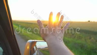 日落时分的人手。 一个人在阳光下从车窗`手，在大自然的<strong>背景</strong>景观上看到阳光。 <strong>荣耀</strong>