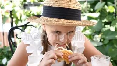 一幅可爱的小女孩戴着草帽在街头咖啡馆里<strong>吃</strong>饭的肖像。 她<strong>吃奶</strong>酪牛角面包，微笑着