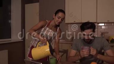女孩在杯子里倒热水，把水壶放在桌子上。 她和丈夫互相看着，微笑着。 然后他们<strong>就来</strong>了