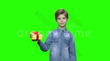 可爱的小男孩用红色丝带指着黄色的礼盒。