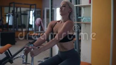 金发女人在健身房做肌肉训练。 运动员在健身房锻炼时，用一个训练者的体重来锻炼身体