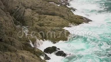海浪撞击岩石海岸. 白色的海水泡沫滴落在岩石上