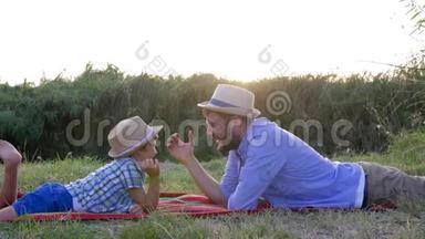 在周末休闲的户外活动中，有爱心的爸爸和孩子一起玩摔跤，躺在格子呢上