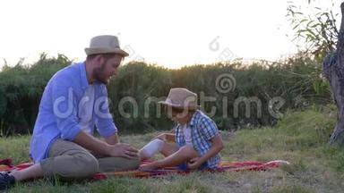 受伤膝盖上有绷带的<strong>农村孩子</strong>正坐在爸爸旁边戴着草帽，竖起大拇指